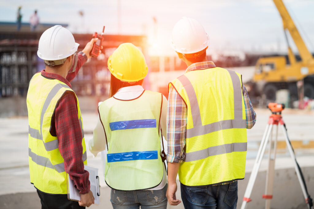 Civil engineers at construction site and a land surveyor using an altometer