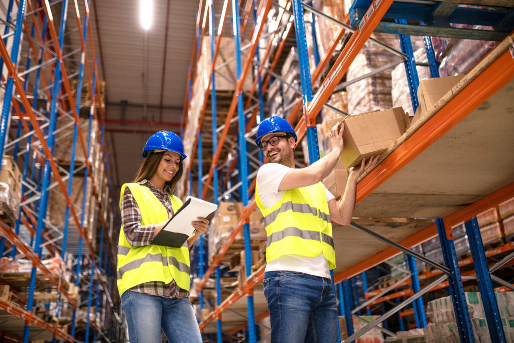 Two young people working together in warehouse storage facility.