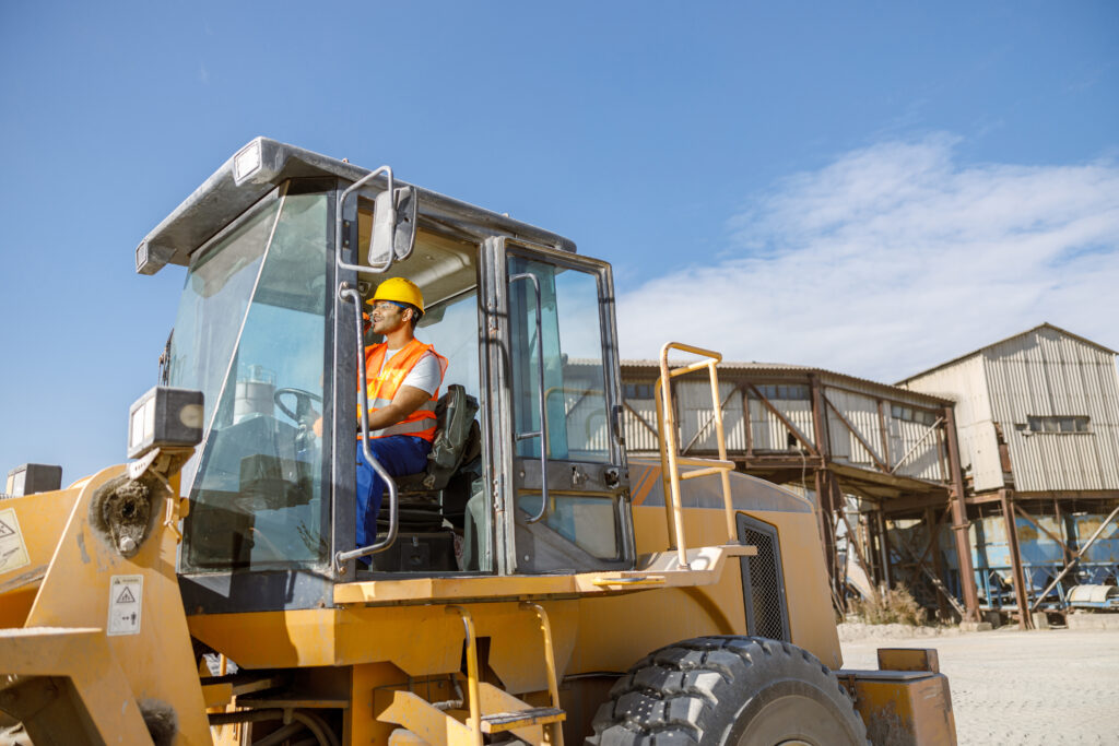 Multiracial construction worker using heavy machinery in plant